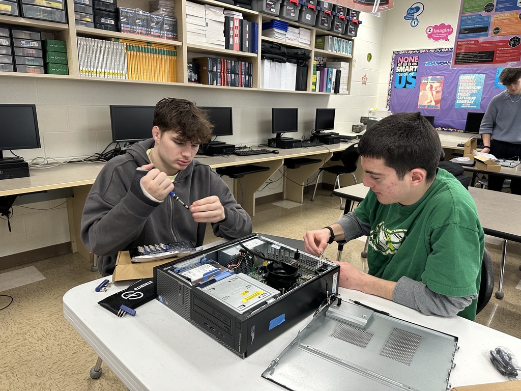 Students taking apart computers to learn more about technology.