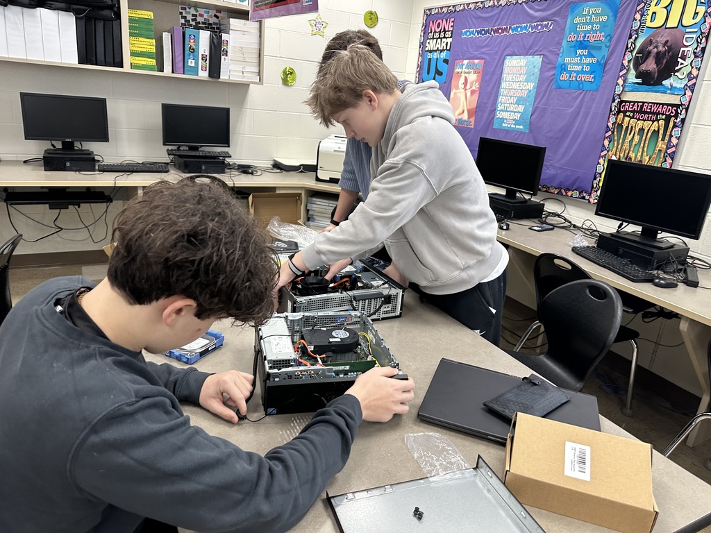 Students taking apart computers to learn more about technology.