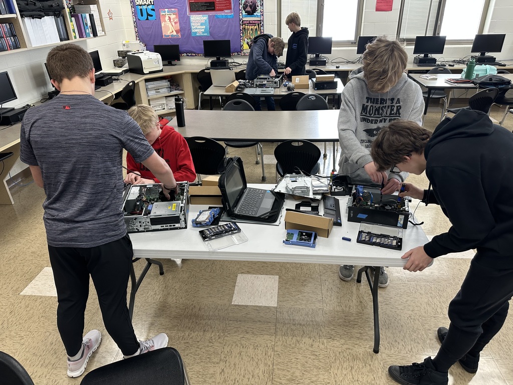 Students taking apart computers to learn more about technology.