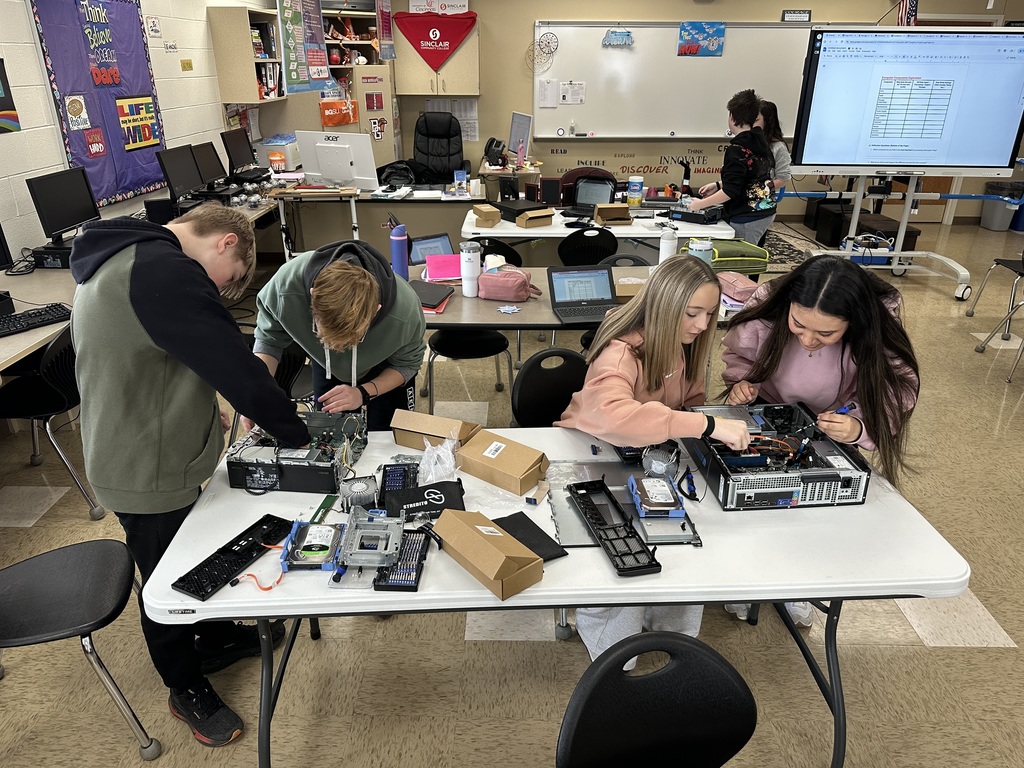 Students taking apart computers to learn more about technology.