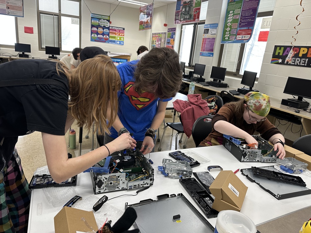 Students taking apart computers to learn more about technology.