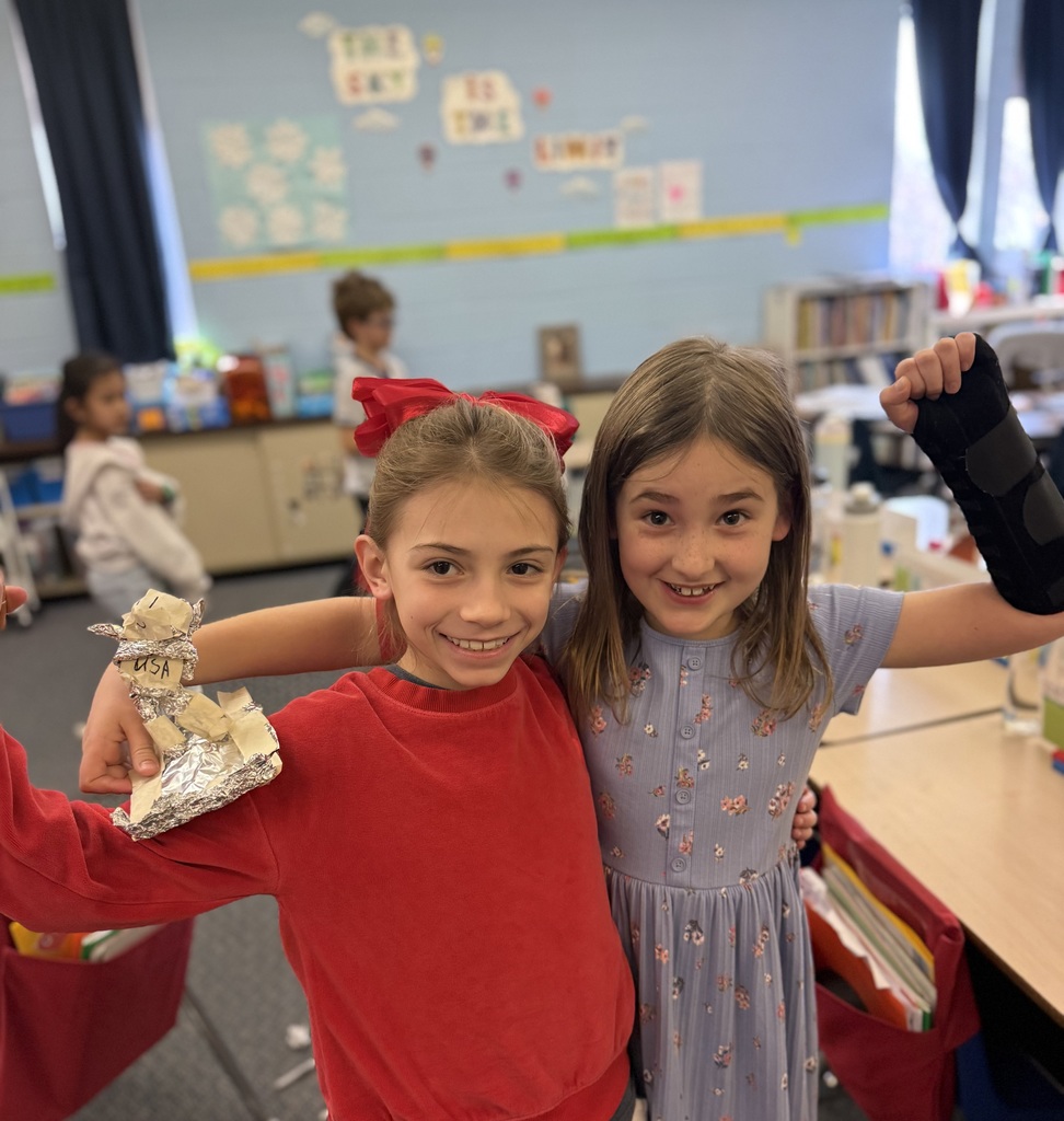 Students show off their skier made out of foil as part of a stem project on speed and motion.
