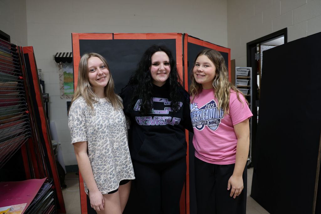 Three TMS students are working on art display boards for an upcoming event.
