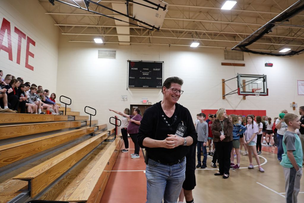 Tracey from Expressions smiles and laughs as he organizes students for a class photo.