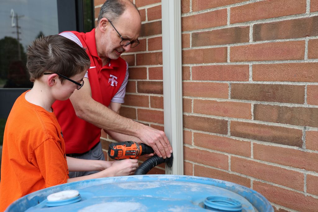 Dale Bonifas helps a student install the rain barrel. 