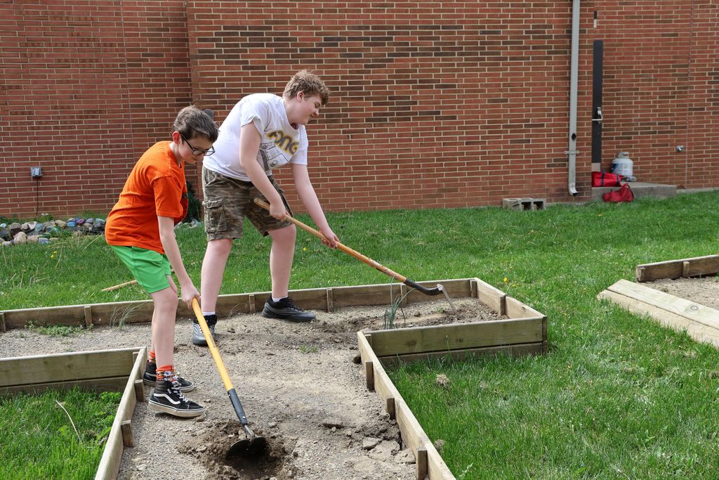 Two TMS students dig and turn the dirt in the garden.  