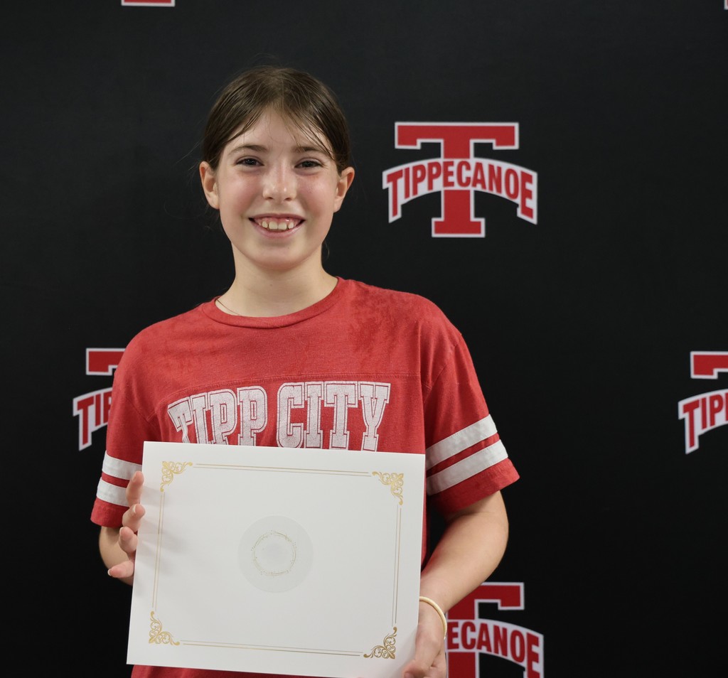 Board of Education honoree from L.T. Ball Intermediate holds her certificate in front of the Tippecanoe backdrop.
