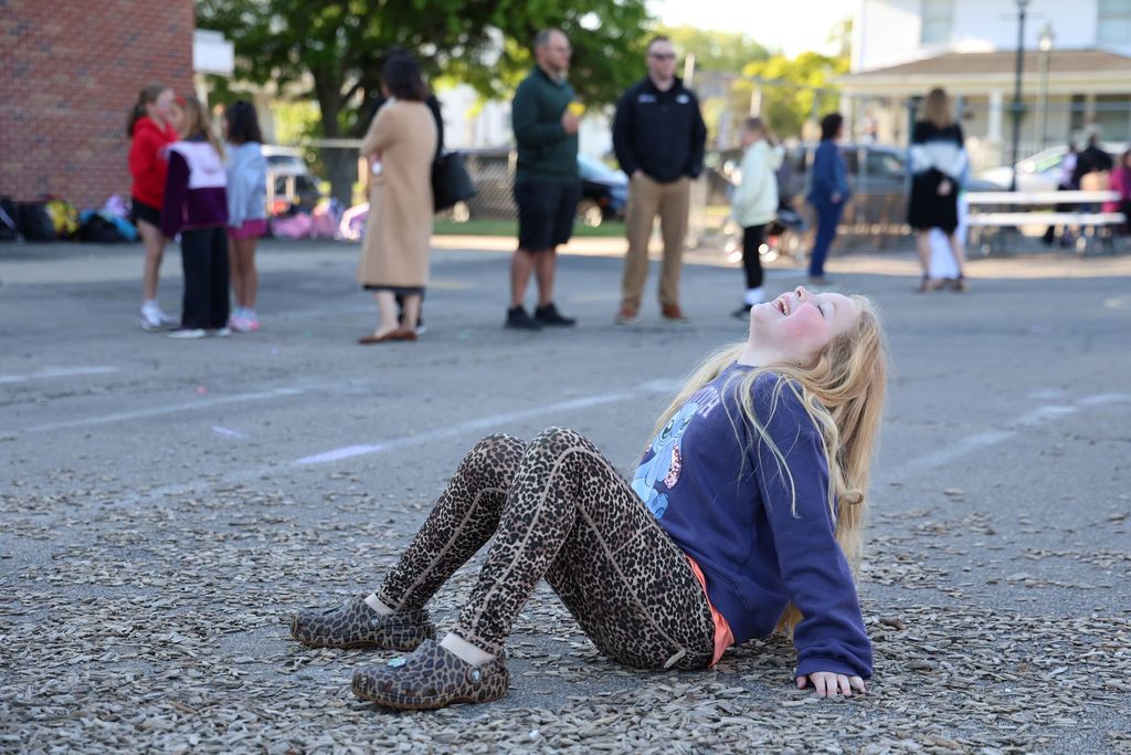 A little girl laughs as she gets silly on the playground.  
