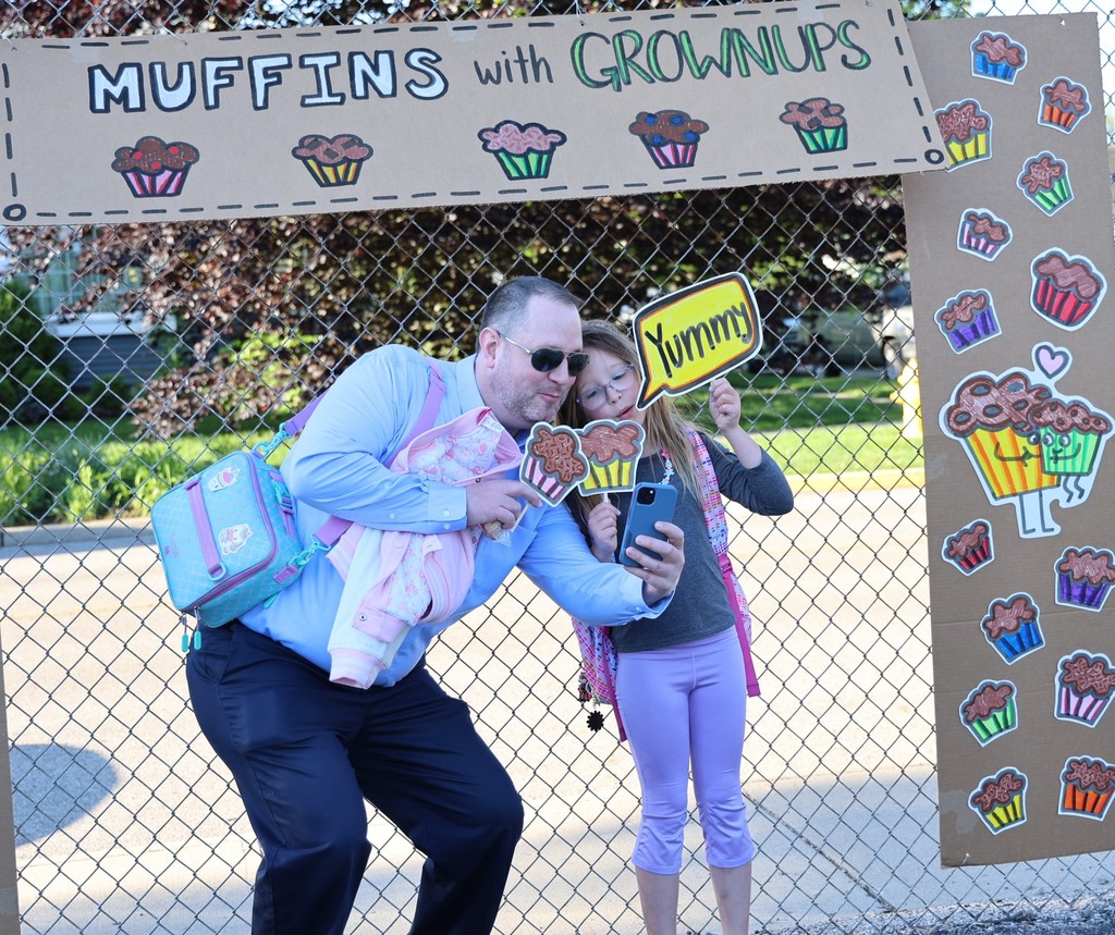 A dad and his daughter taking a selfie with photo props. 