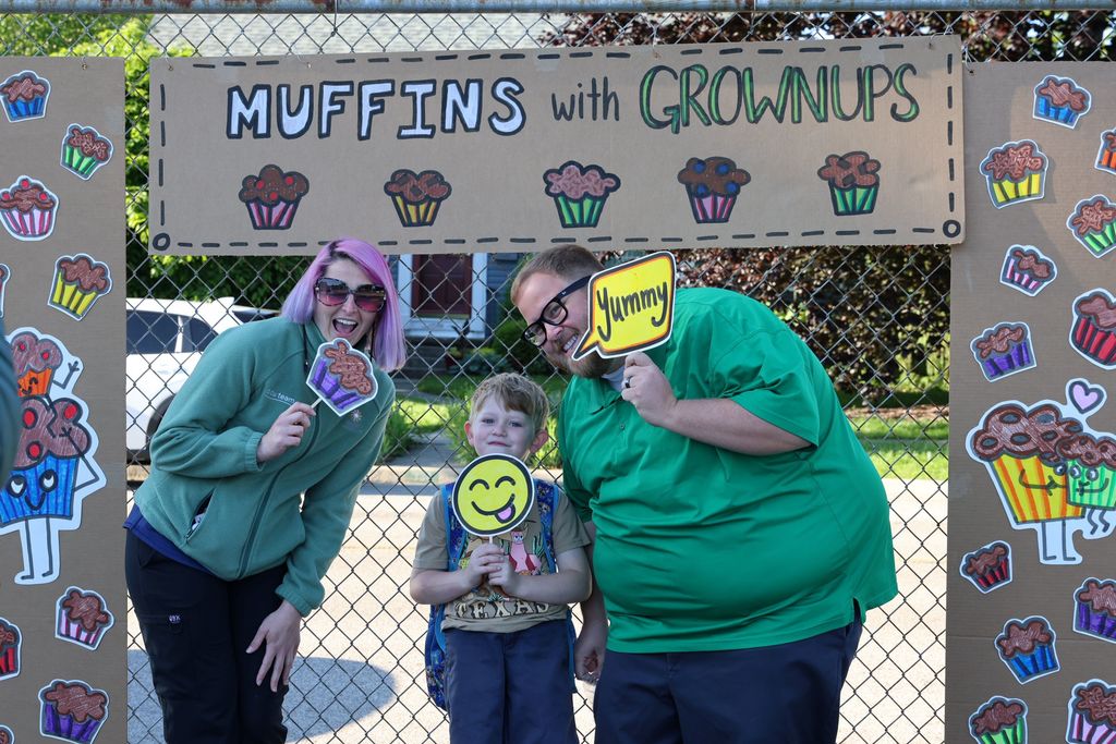 Mom and dad with their son at Muffins in the Morning.  They are being silly with photo props.  