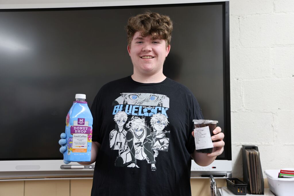 A student holds up coffee for delivery.  