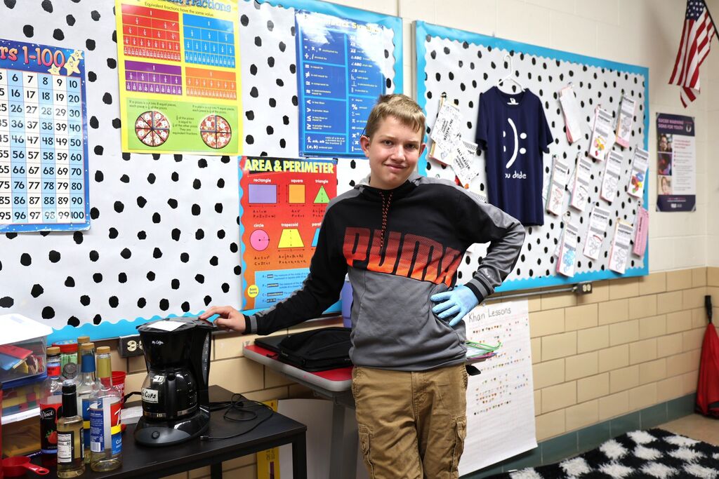 A student shows off the coffee machine used to brew hot coffee. 
