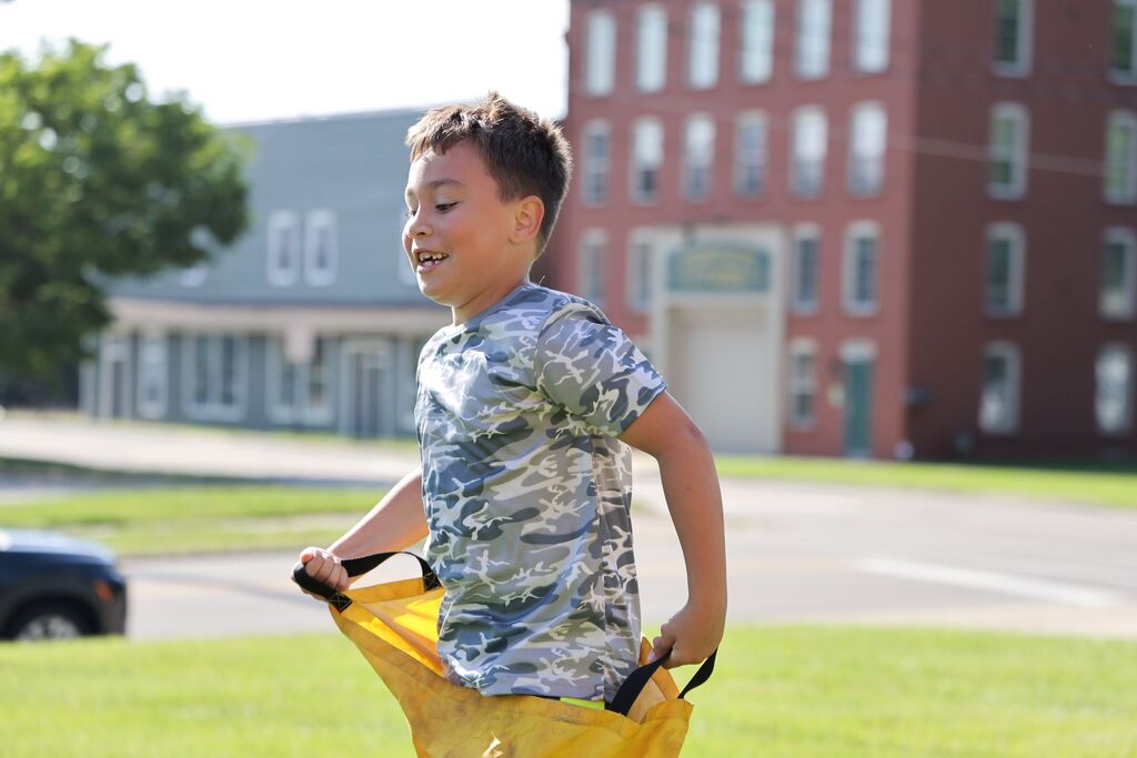 A Broadway student is all smiles as he races in a potato sack.  
