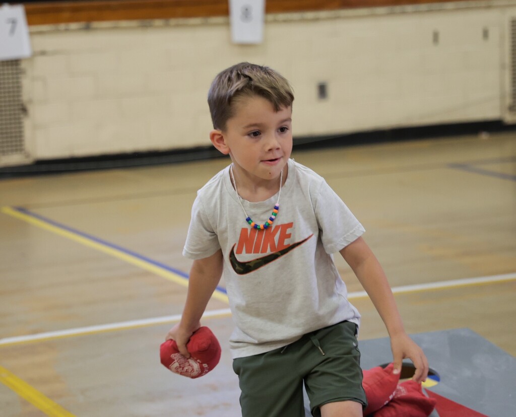 A little boy gets ready to toss the bean bag. 
