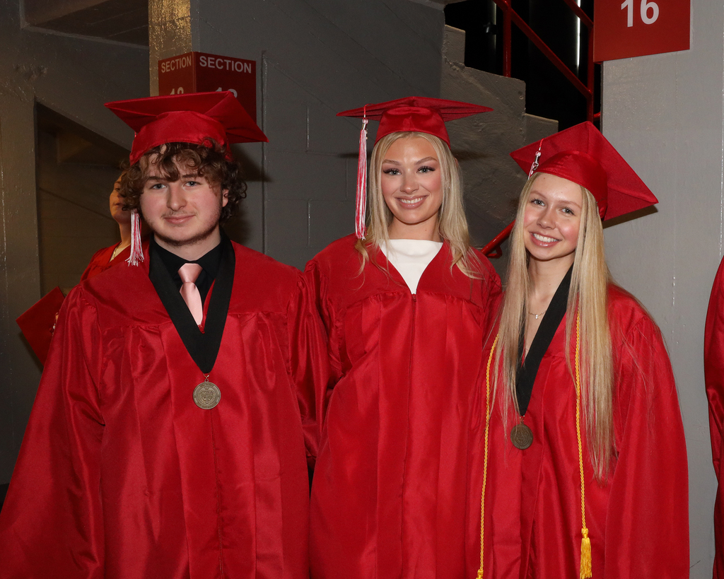 Three students before graduation pose for a photo.