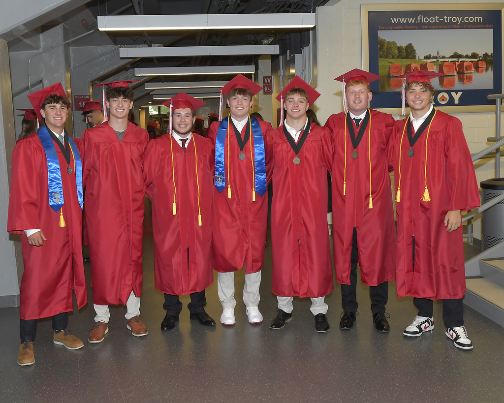 A group of boys stand together for a photo before graduation.