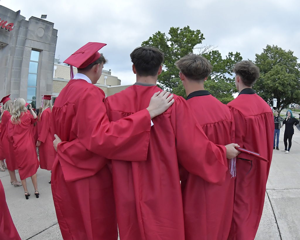 The backs of four friends as they pose for a photo after graduation. 