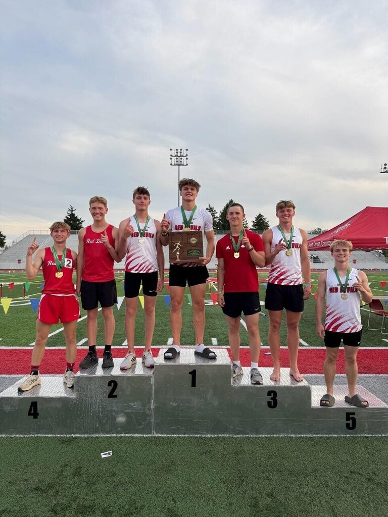 Track and field medal winners take a group shot on the podium. 