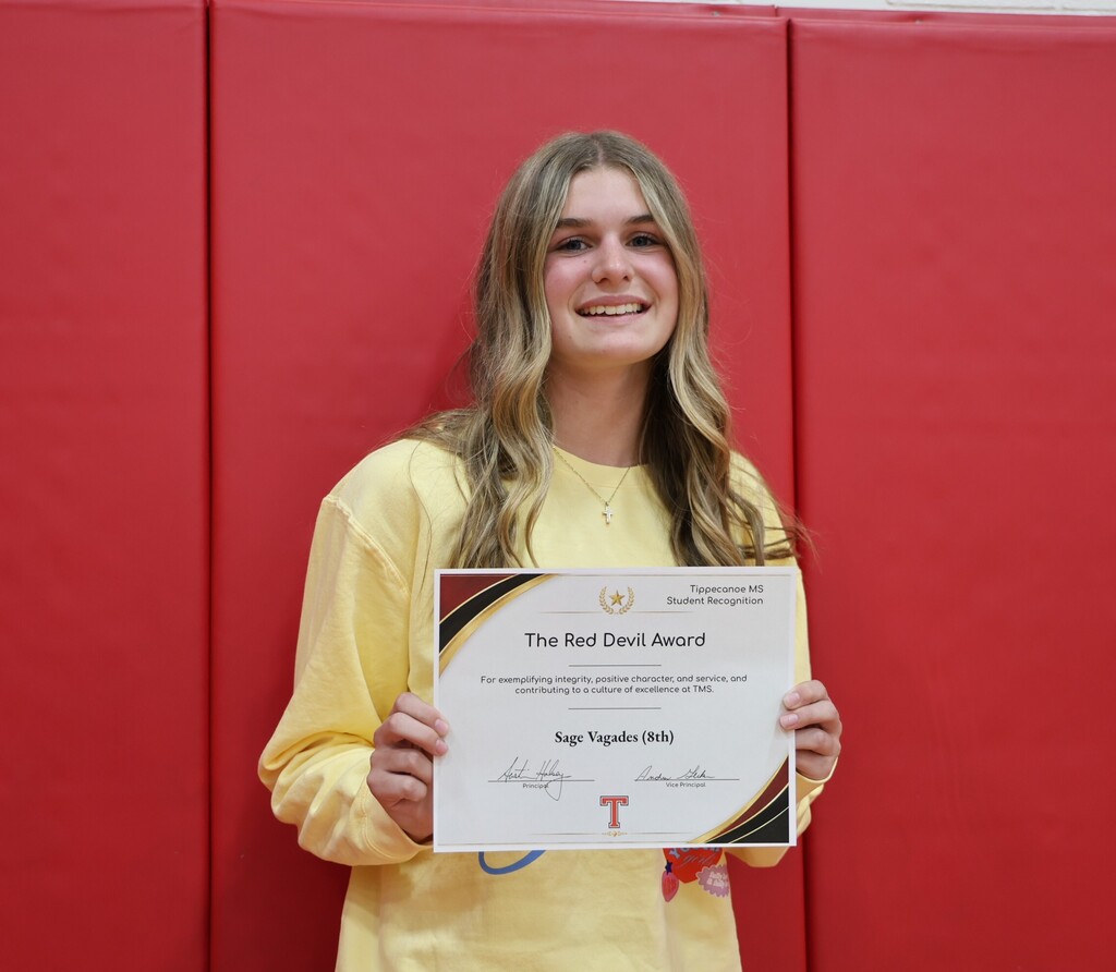 TMS student holds her certificate for earning the Red Devil Award.
