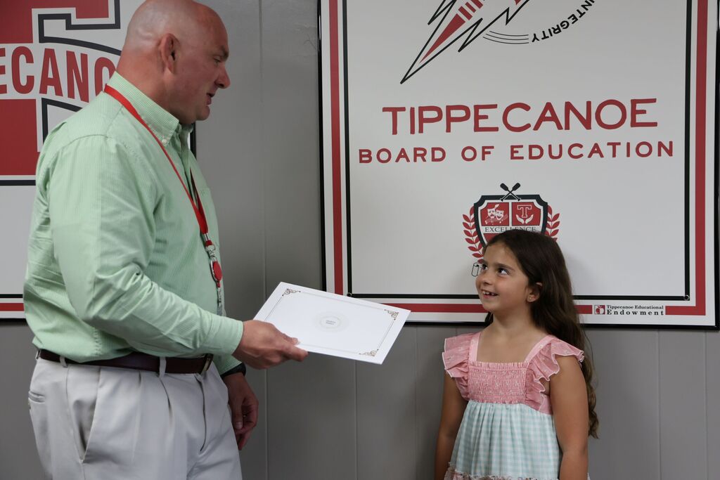 The district superintendent handing a certificate to a student.