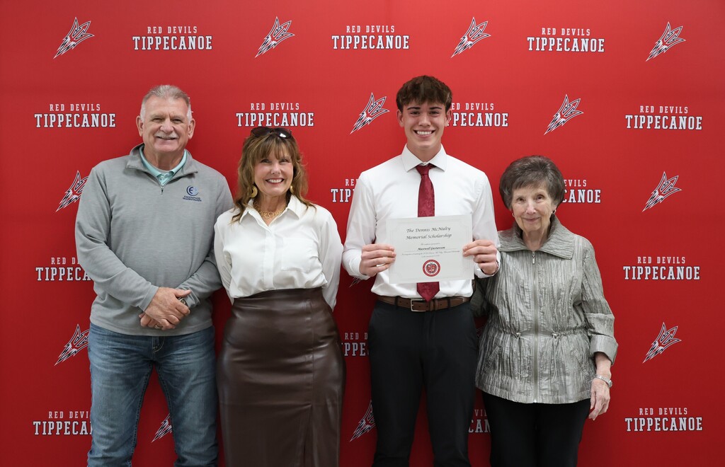 Class of 2026 graduate stands with the McNulty family after receiving the family  scholarship.