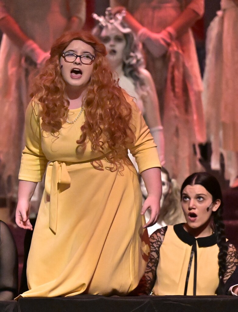 A THS student in a yellow dress performs in the spring musical, The Addams Family.