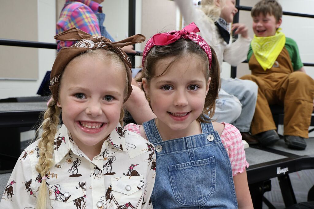 Two girls smile for the camera as they wait to be in their spring performance. 