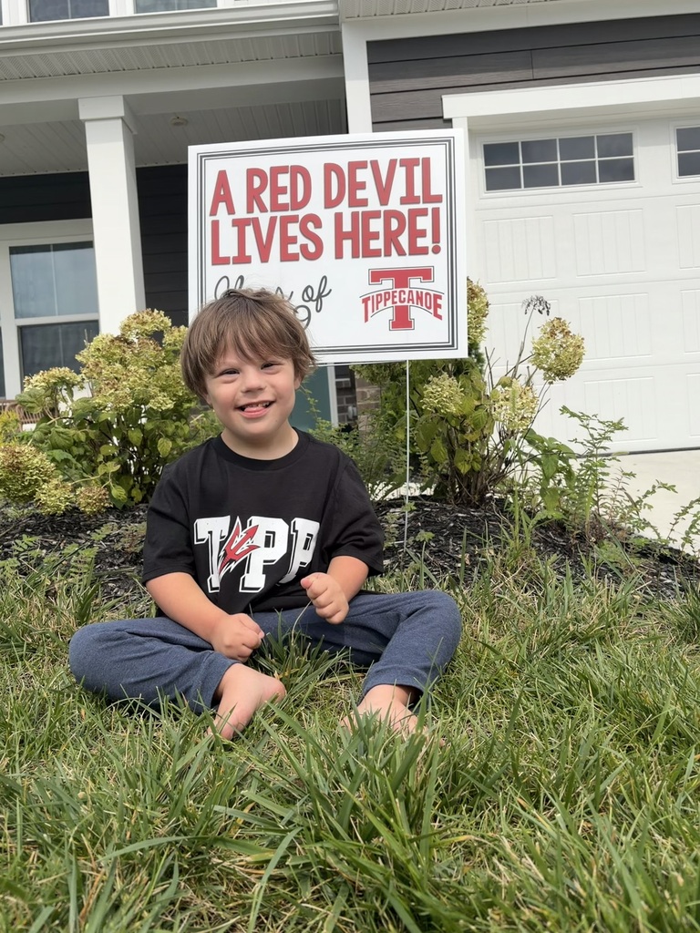 A kindergarten student with a yard sign, Class of 2039, to welcome them to school.