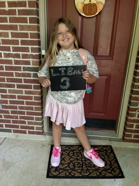 A student poses for her first day of school photo.