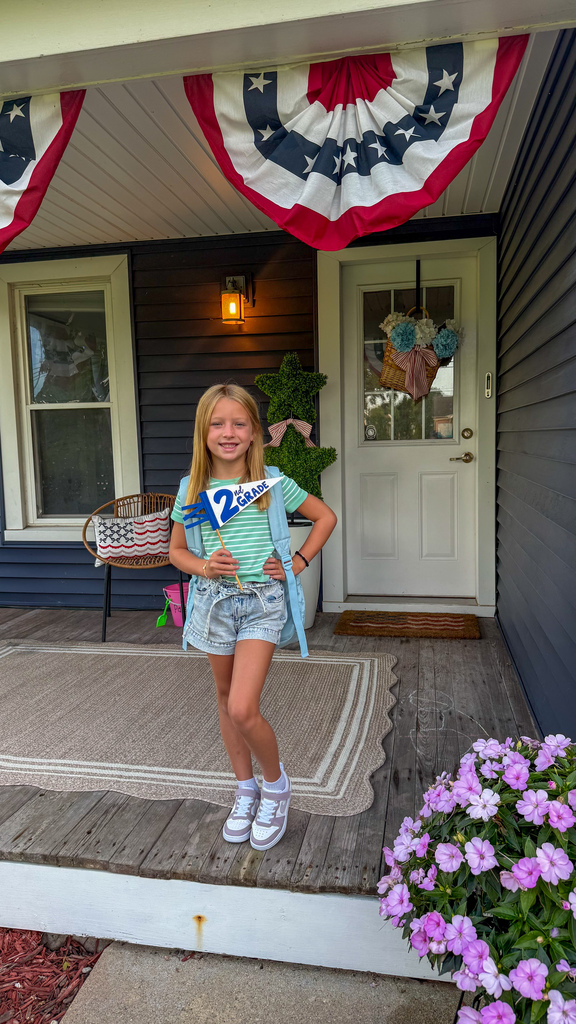 A second grader poses for her first day of school photo.
