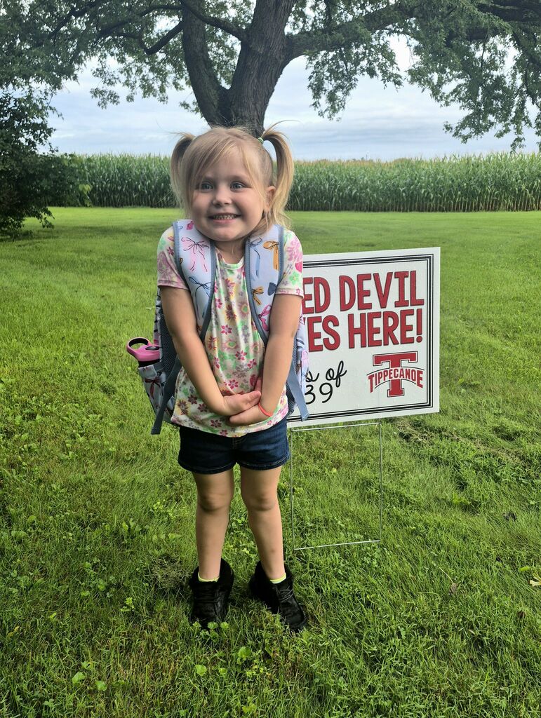 On the first day of school a kindergarten student poses with the Class of 2039 sign.