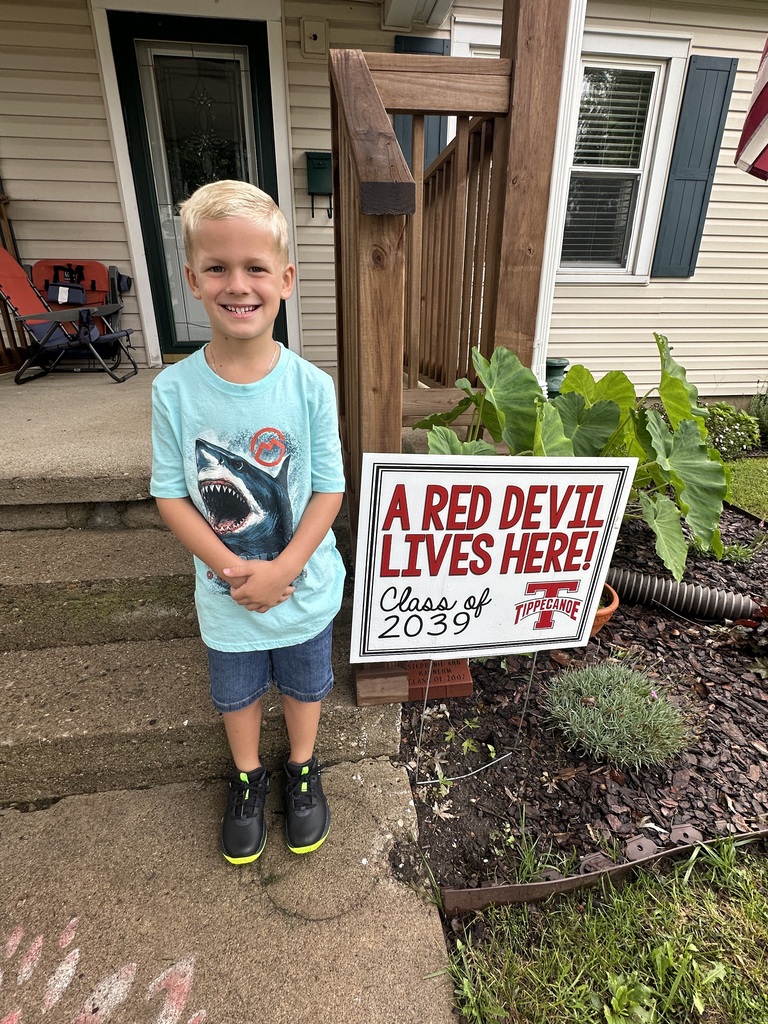 On the first day of school a kindergarten student poses with the Class of 2039 sign.