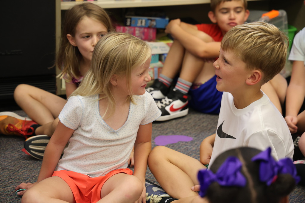 Students make silly faces during story time as they act out the pages of The Book of Rules.