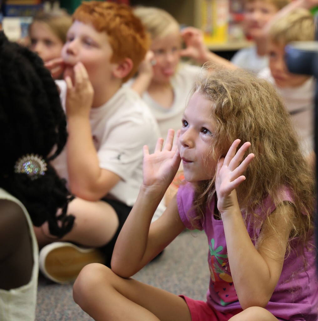 Students make silly faces during story time as they act out the pages of The Book of Rules.