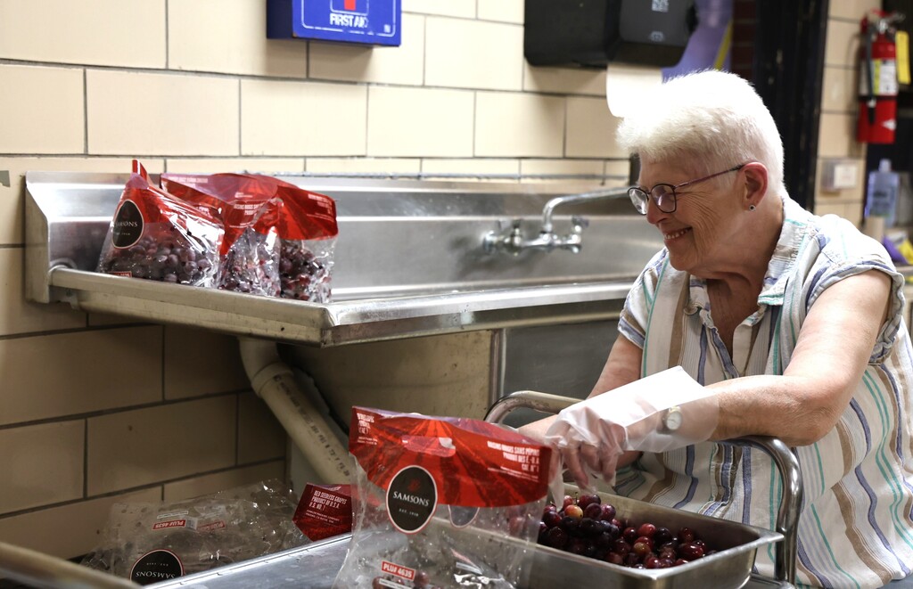 A Broadway Elementary kitchen staff member washes and cuts grapes for lunch.