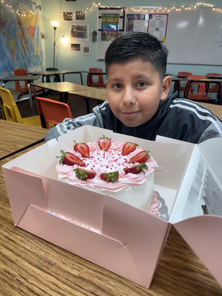 A TMS student poses with a beautiful cake made by his grandmother as part of his class presentation.