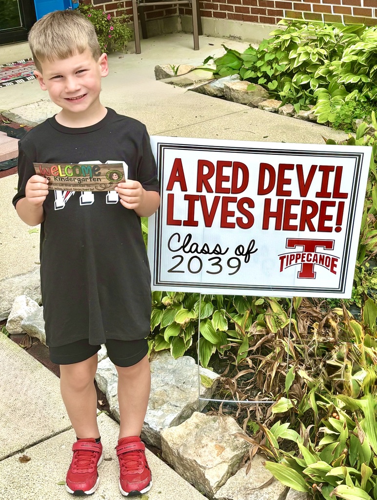 A students stand in front of his class sign.
