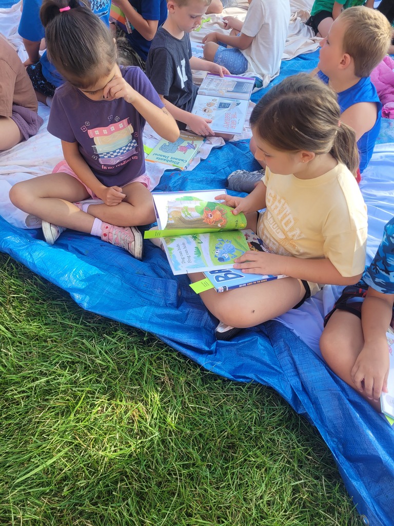 Broadway Elementary student reading books on the lawn.