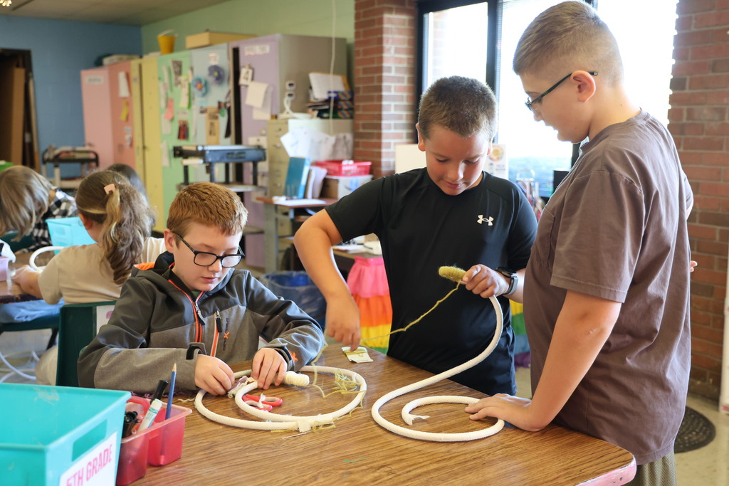 L.T. Ball fifth graders are learning how to weave a basket.  A student helps two of his classmates.  
