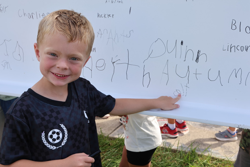 A Broadway Elementary students shows off his name after signing the steel beam for the new school. 