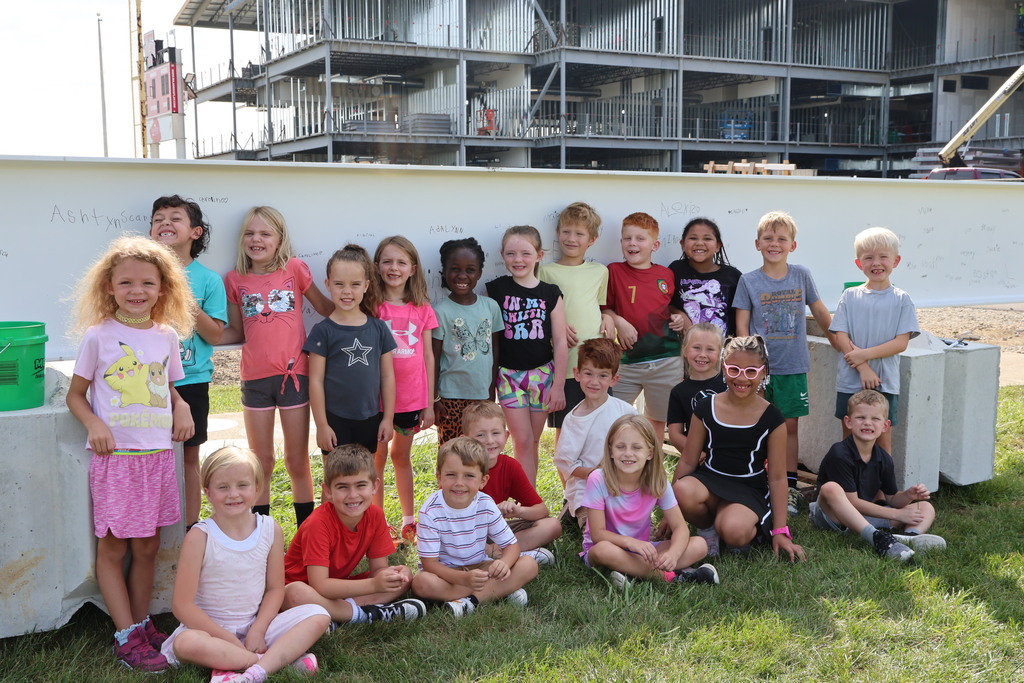 A Broadway Elementary students pose in front of the steel beam they signed that will go in the new school.  