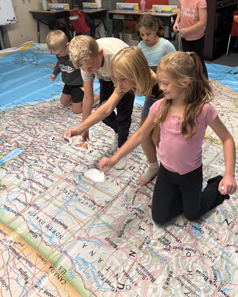 Students sit on a map and get their butterflies ready for migration.