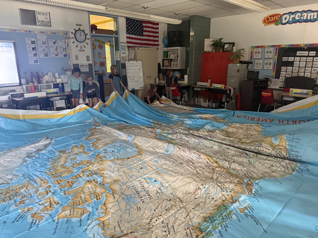Students roll out the huge map that is the size of their classroom.