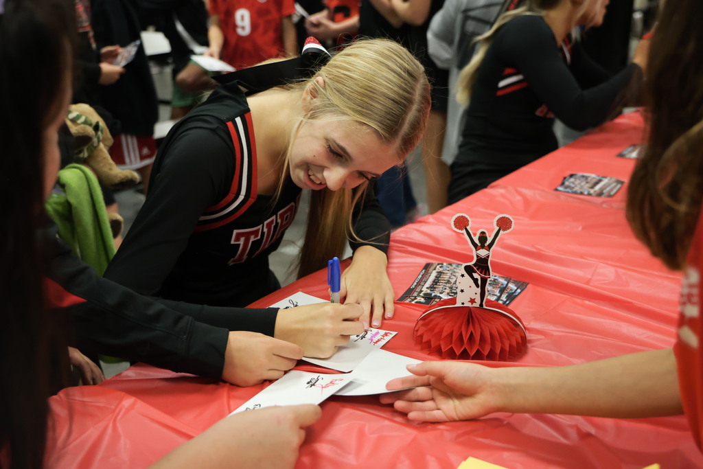 A cheerleader signs her autograph.