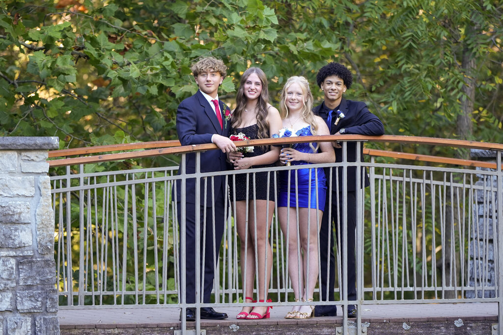 Photo of four THS students dressed up for prom and posing on a bridge.