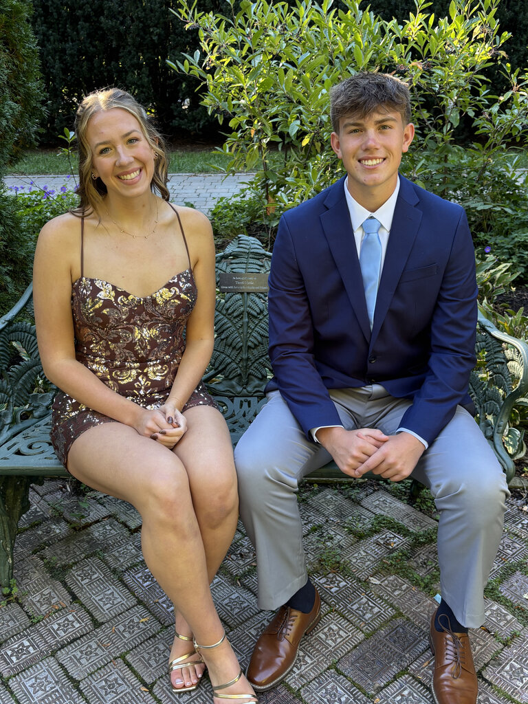 Two students pose for a photo sitting on a bench before the Tippecanoe High School homecoming.