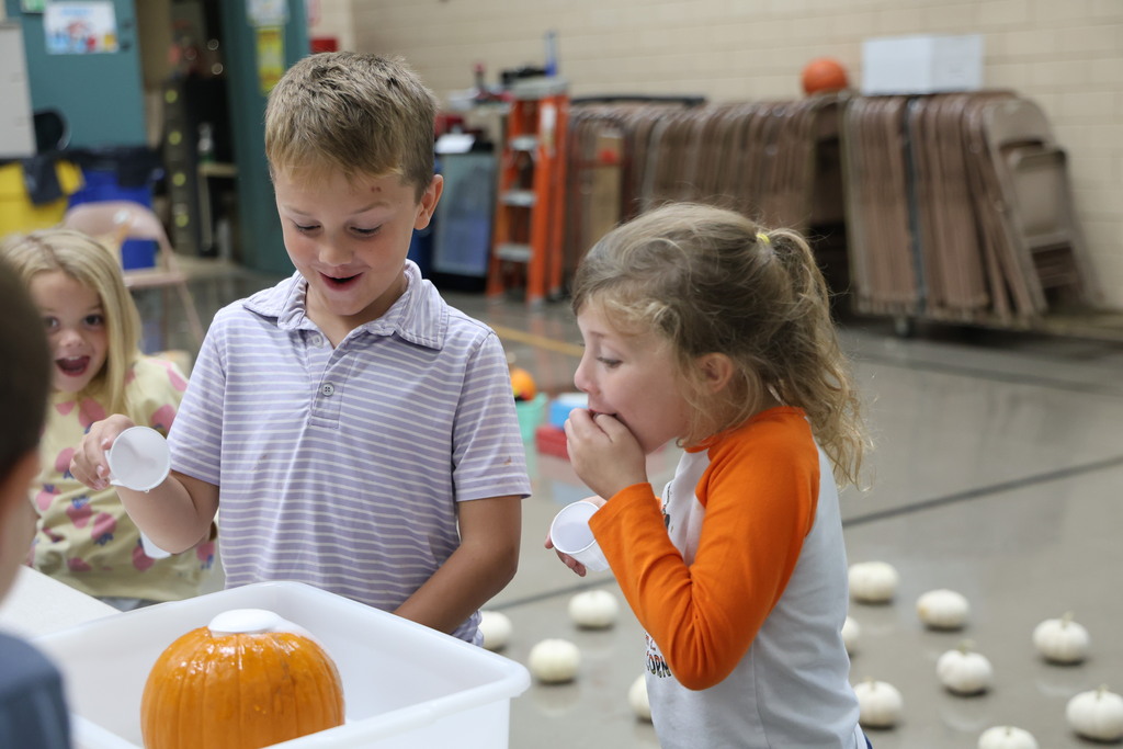 Two students react at the chemical reaction of combing baking soda and vinegar.