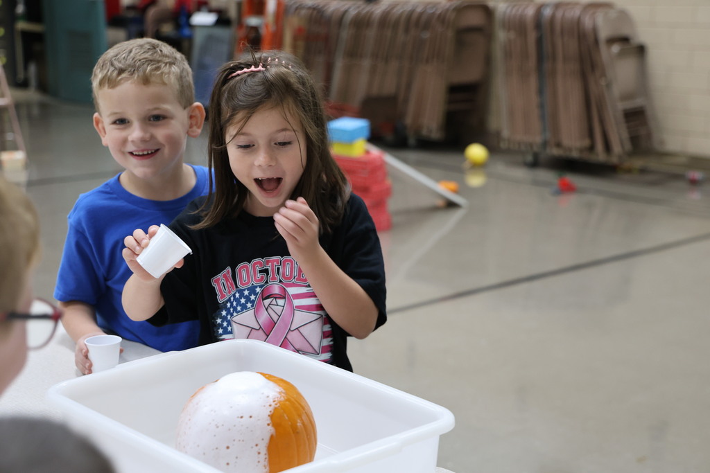 Two students react to what happens when you add vinegar to baking soda inside a pumpkin.