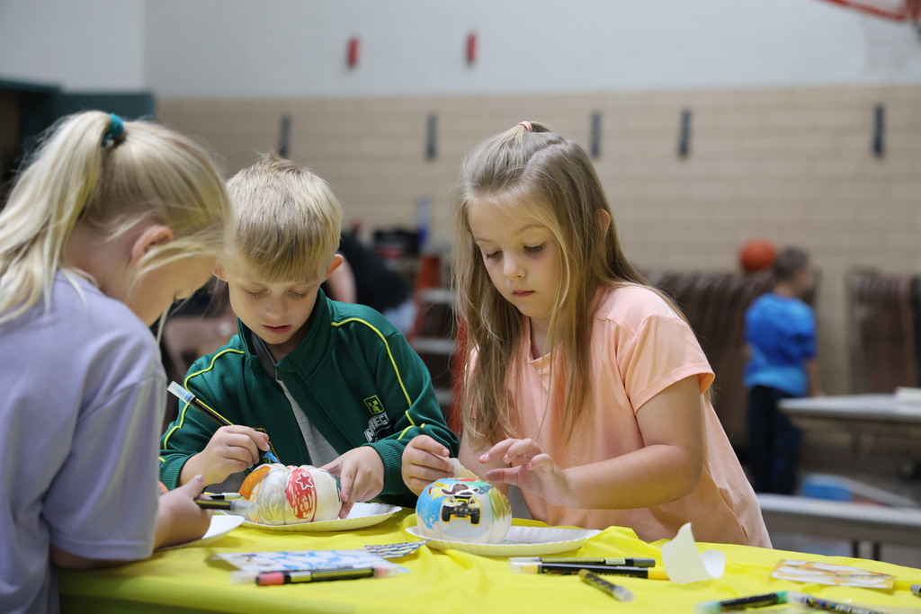 Two students are very intent as they decorate their small pumpkins.