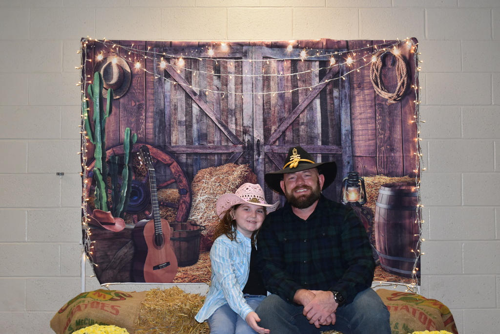 A father and his daughter pose for a photo at the hoe down.  